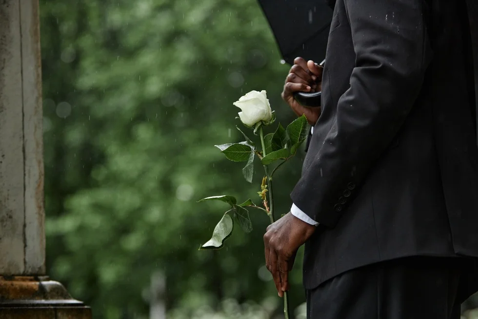 man holding white rose on funeral