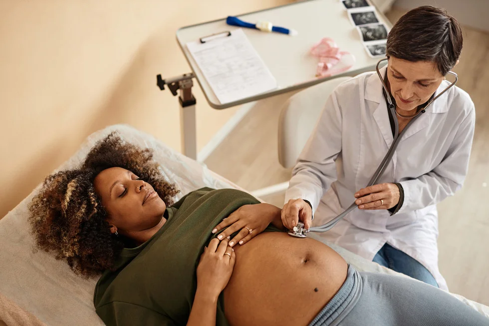 nurse-with-expectant-mother-using-stethoscope-check
