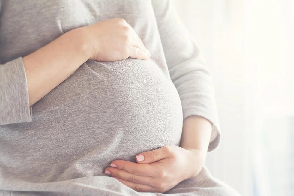 pregnant holding bump with one hand on top and one under
