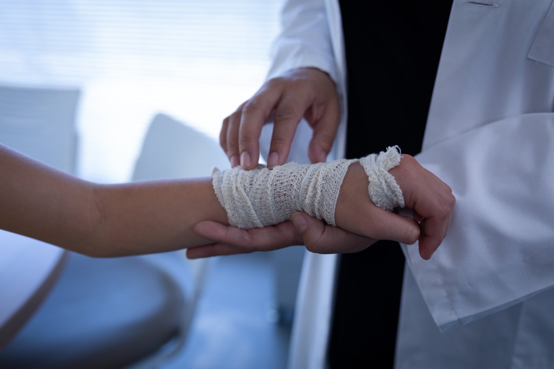 Doctor examining a patient’s bandaged wrist in medical office
