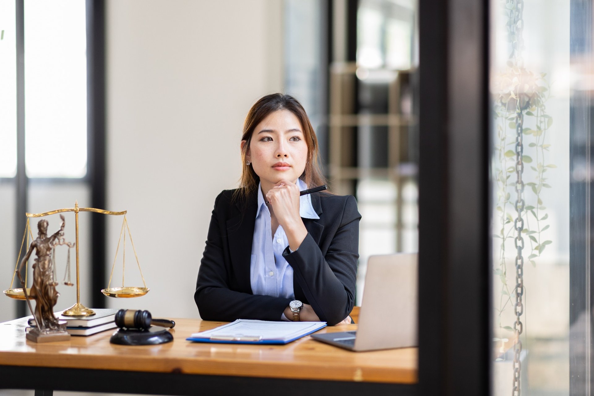 Female lawyer sitting at desk with legal documents and thinking