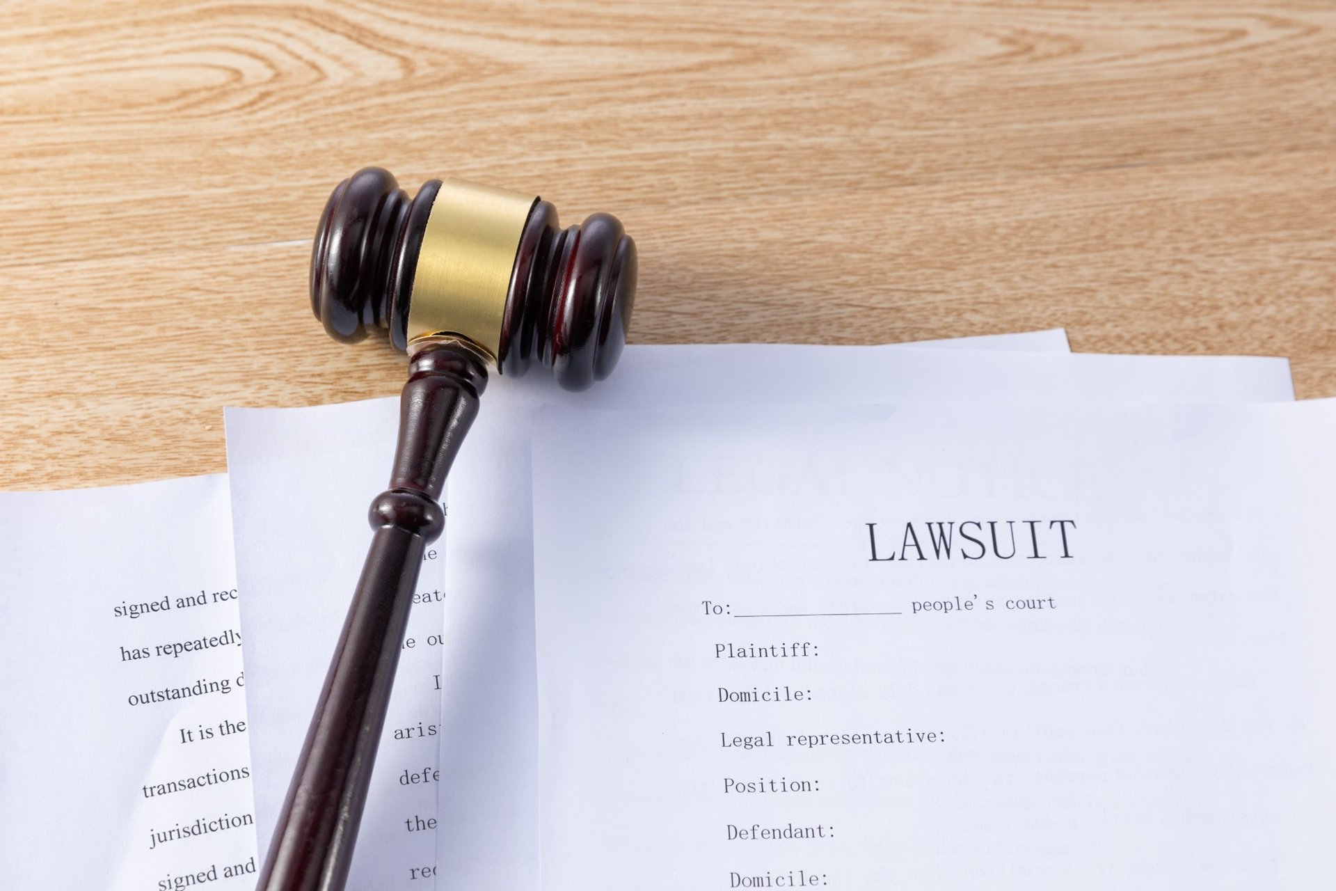 Lawsuit documents and a judge's gavel on a wooden desk