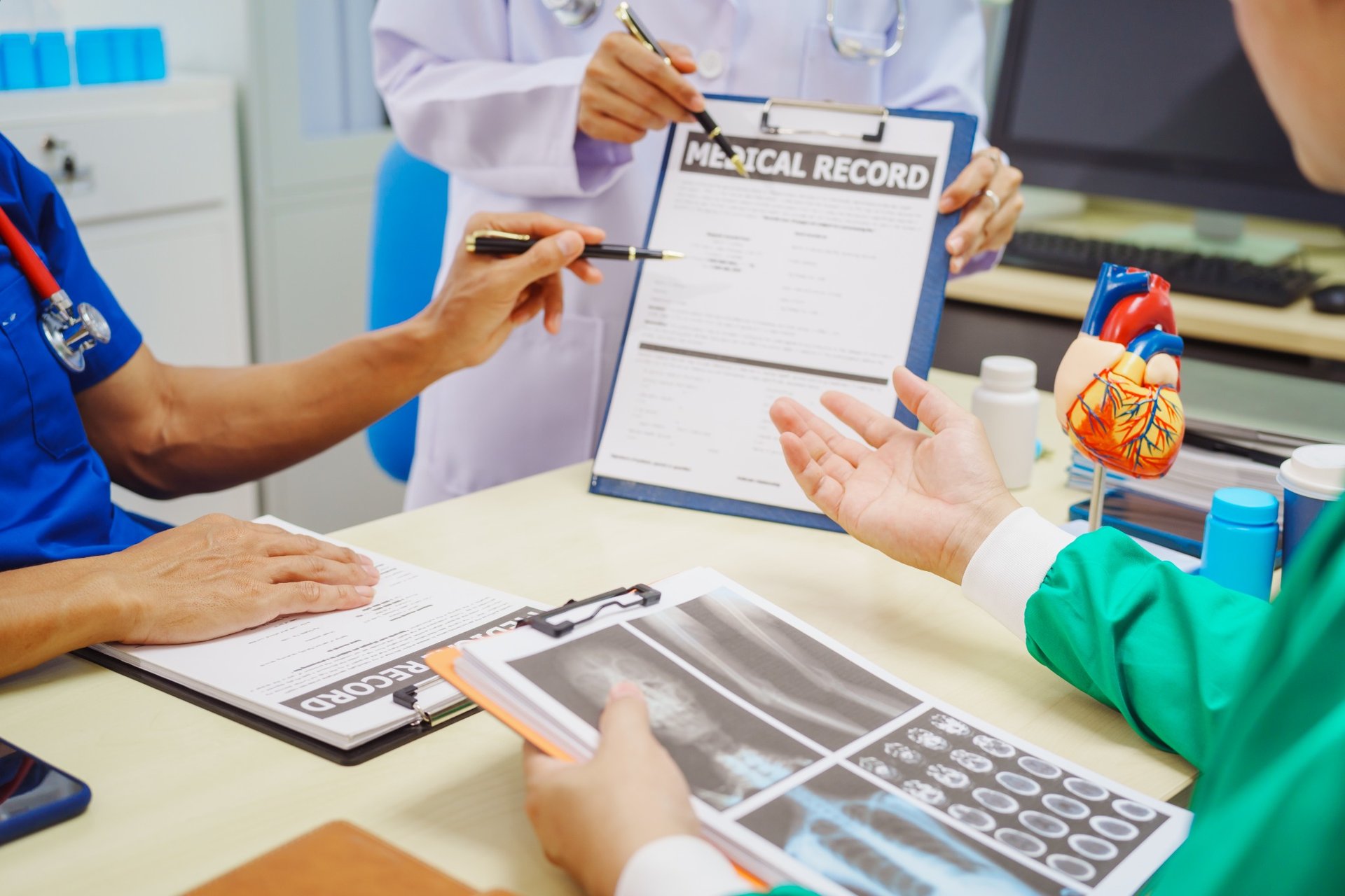 Medical professionals reviewing records and x-rays at hospital desk