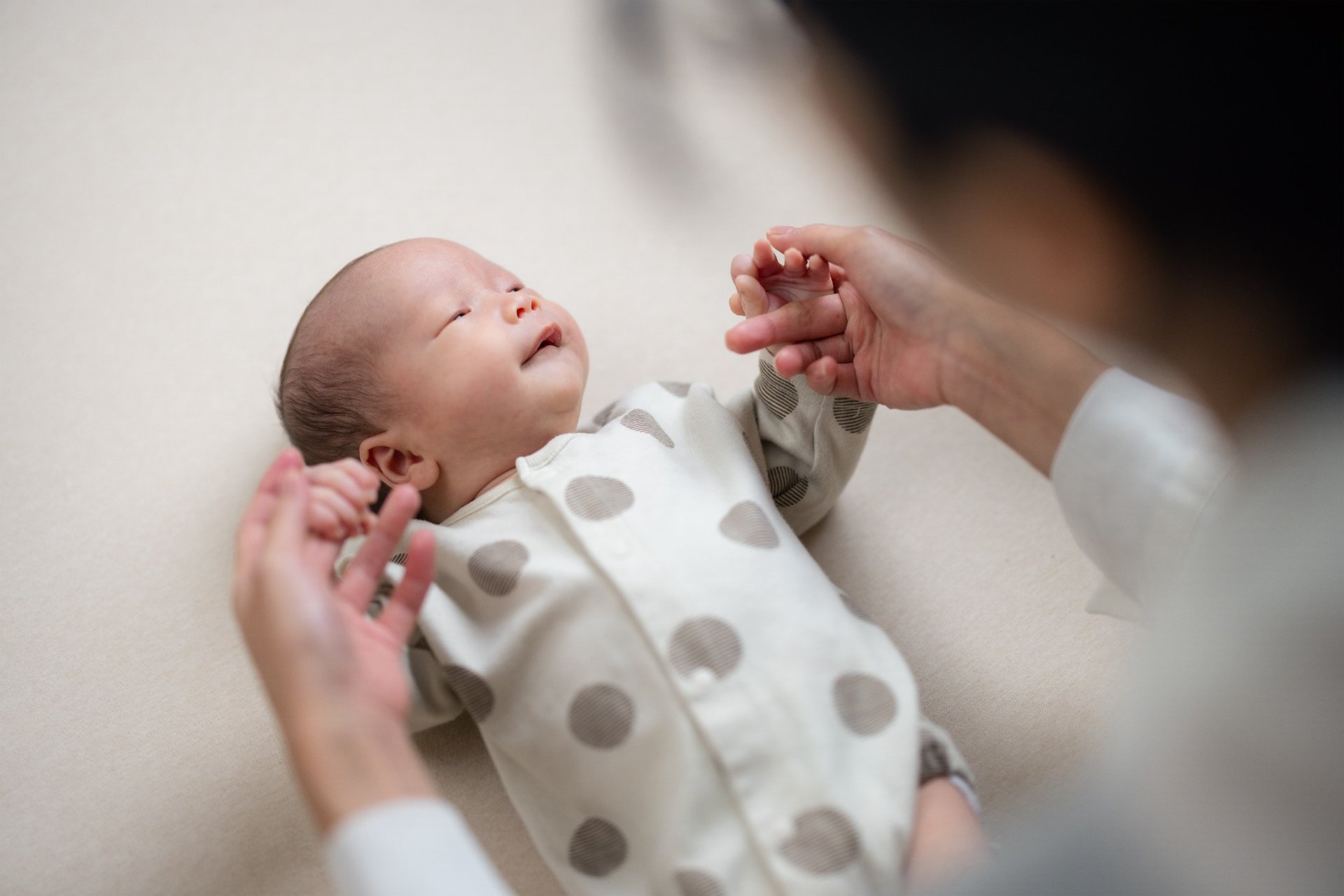 Mother holding newborn baby’s hands during early exercises