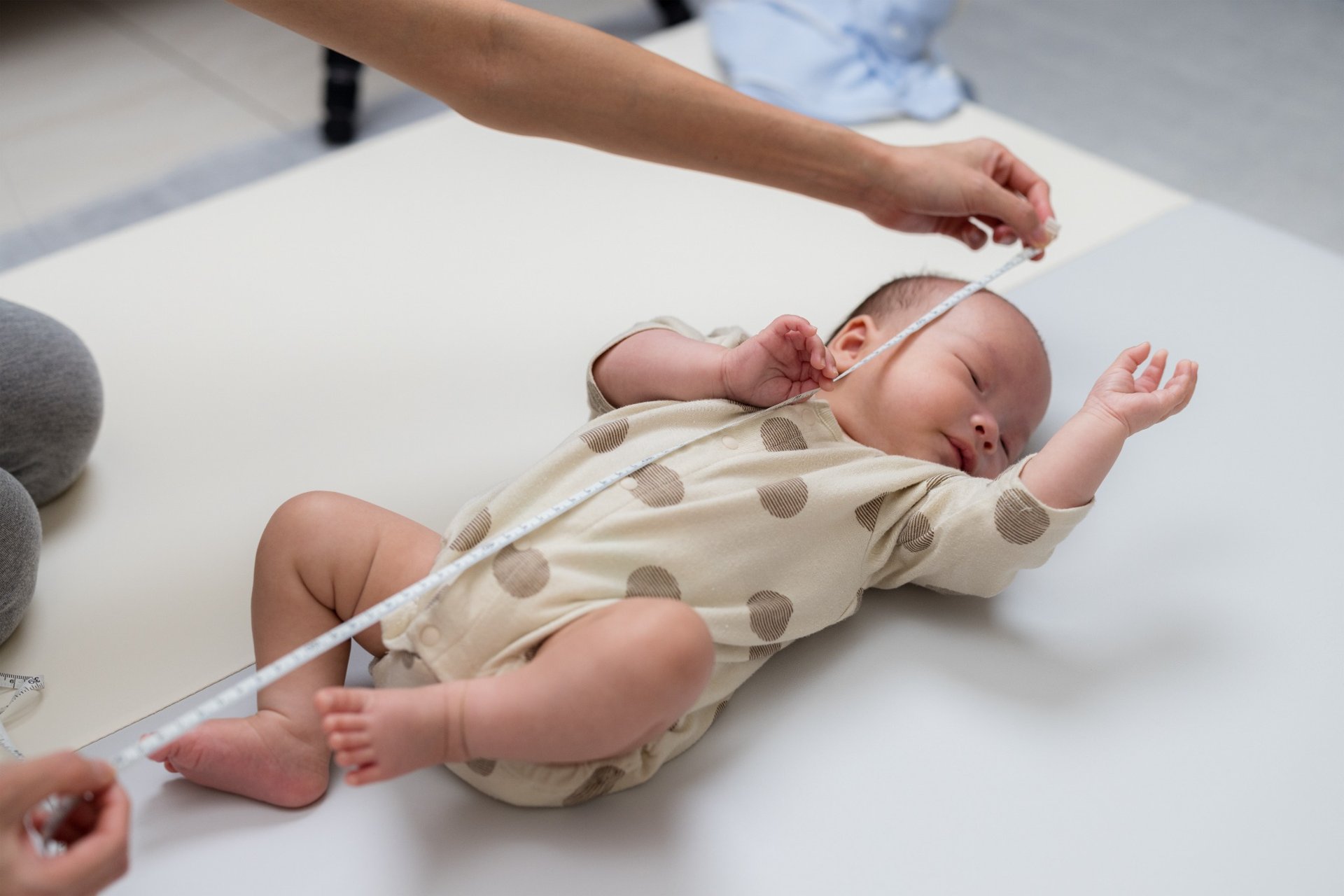 Newborn baby being measured with tape by caregiver