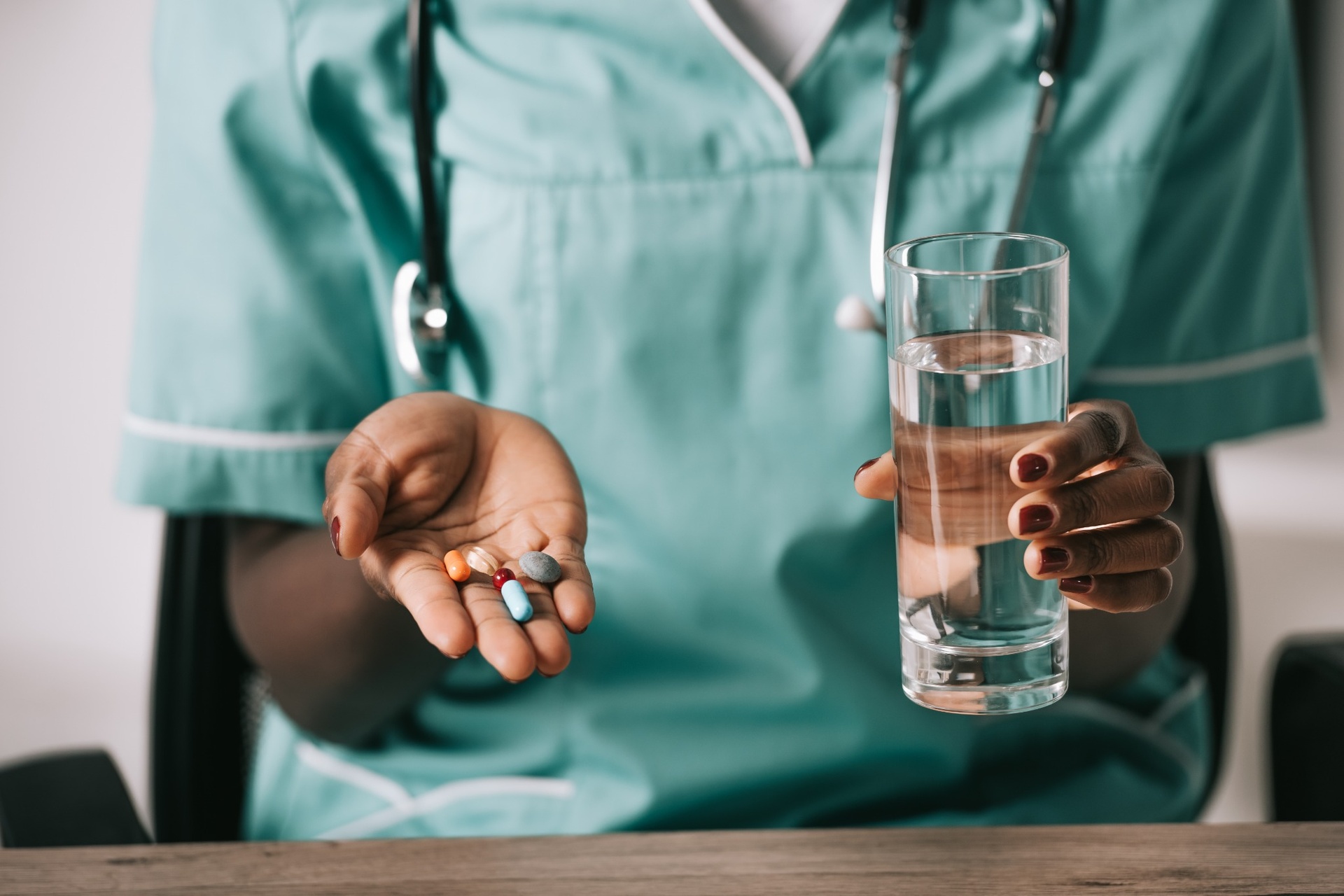 Nurse holding pills and a glass of water for patient medication
