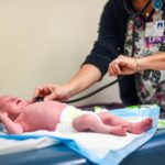 Nurse performing a health check on a crying newborn baby