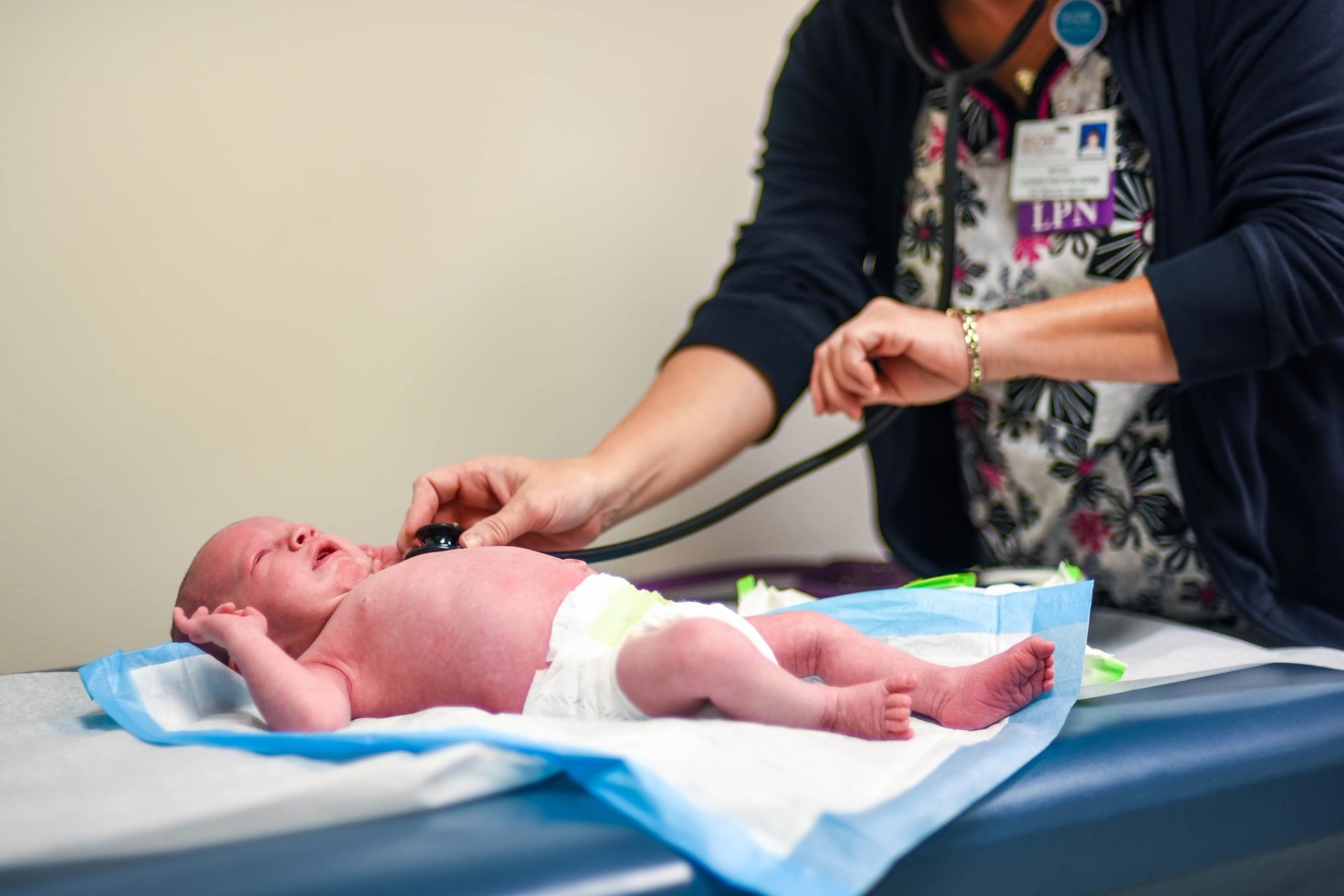 Nurse performing a health check on a crying newborn baby