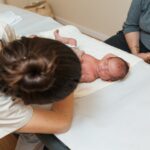 Physiotherapist working with a newborn baby on a table