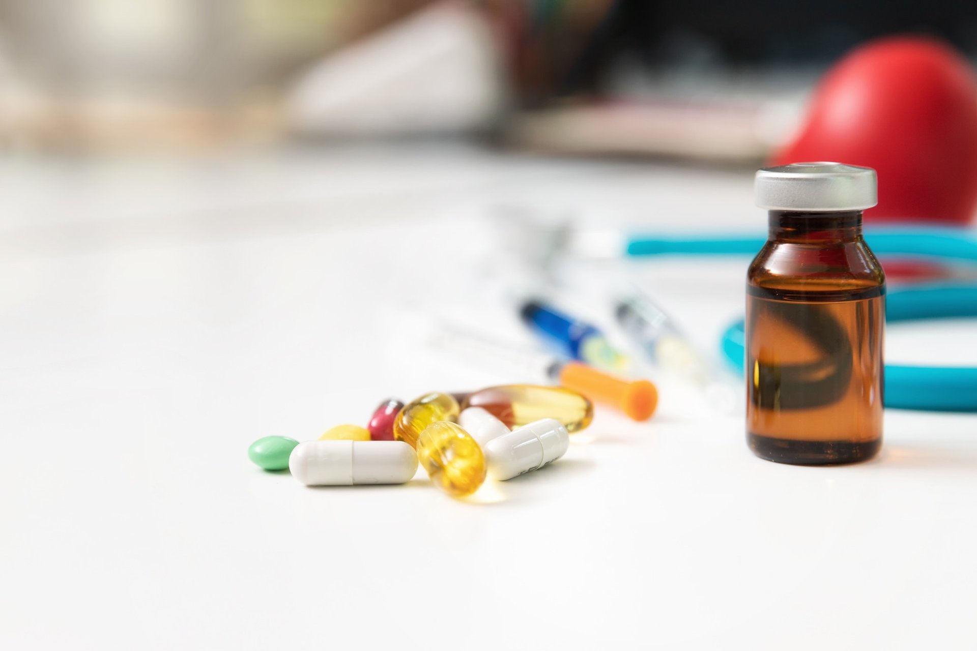 Pills, syringe, and medication vial on clinical surface