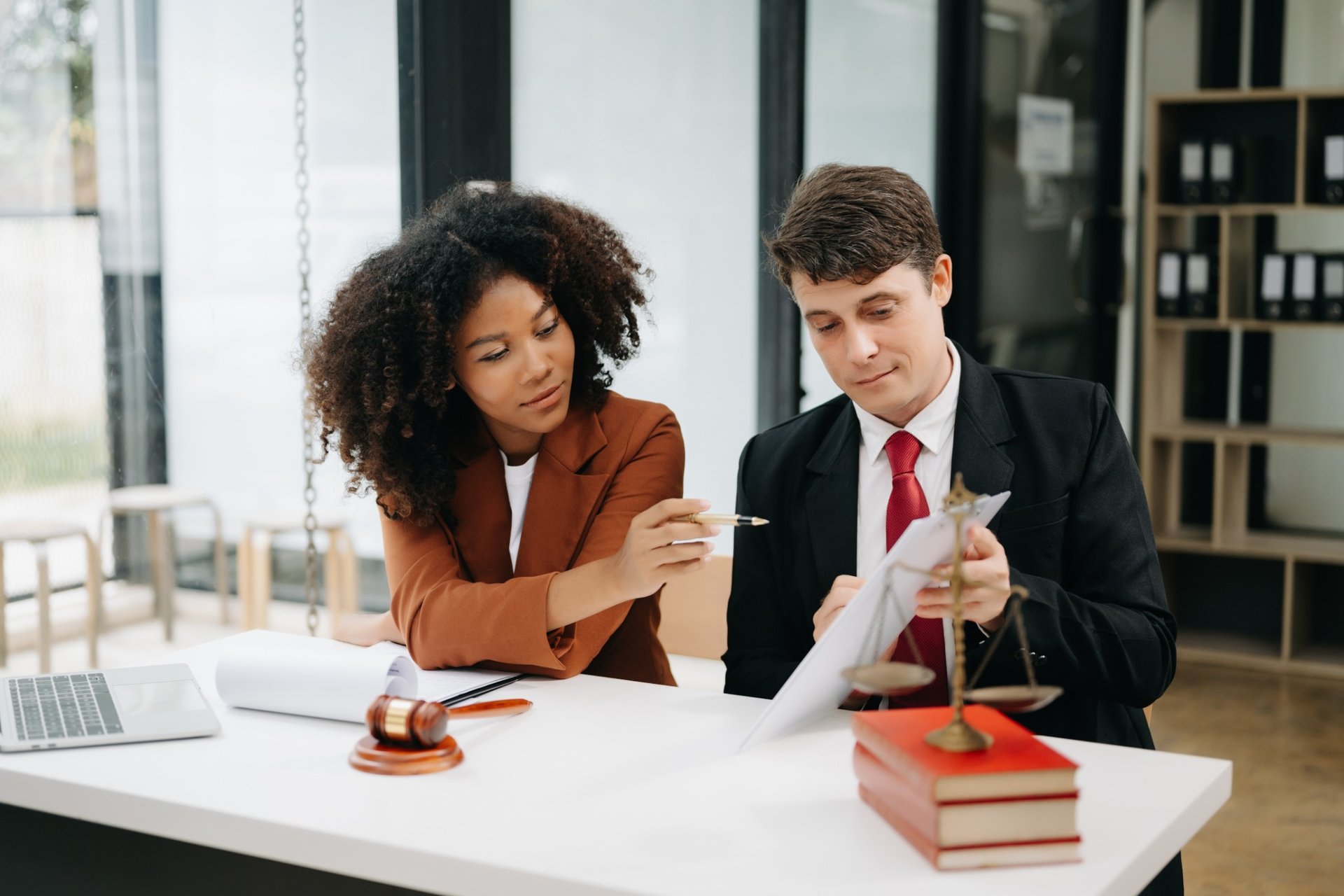 Two lawyers reviewing a legal document at a white desk with a gavel